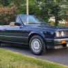 A black 1990 BMW 325i E30 convertible parked with the top down in right front angle view