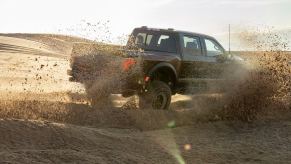 A 2024 Ford F-150 Raptor, one of the Ford F-Series lineup of best-selling pickup truck models in America, kicks up sand.