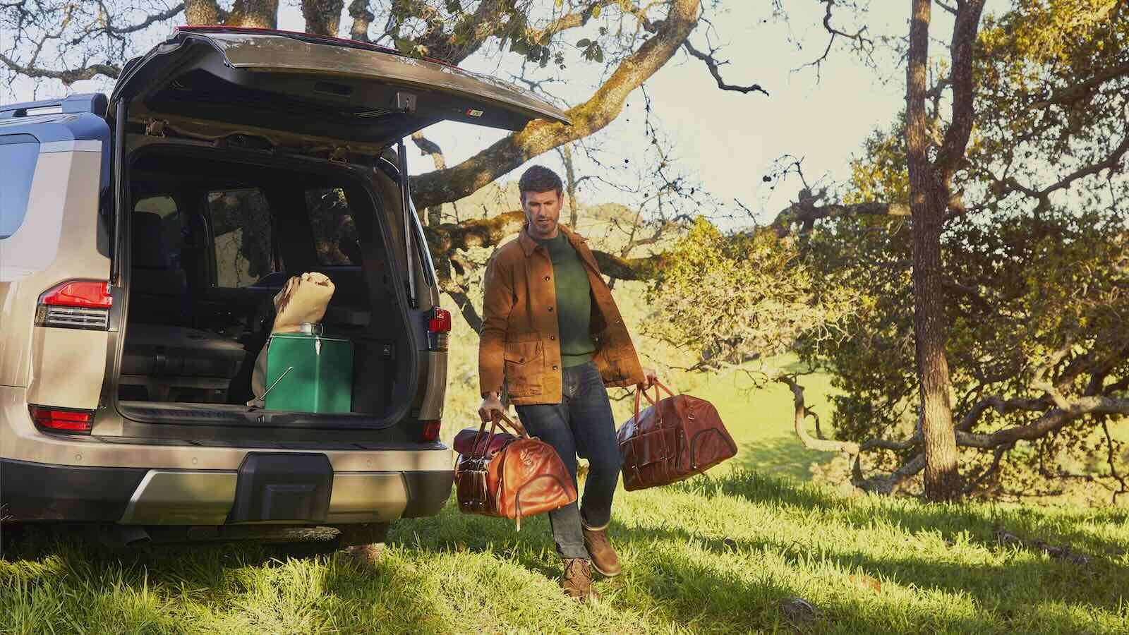 2024 Lexus GX driver carries his luggage through a grassy field, his SUV visible in the background.