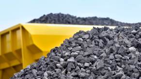 Yellow dump truck leaves a load of gravel on the ground.