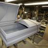 Casket maker shapes an extra-large 48-inch casket out of steel in a workshop.