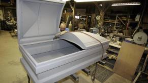 Casket maker shapes an extra-large 48-inch casket out of steel in a workshop.