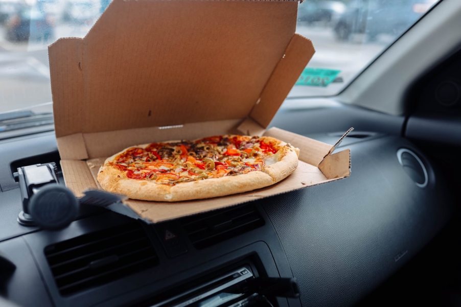 Box of pizza on the dashboard of a Honda fit car