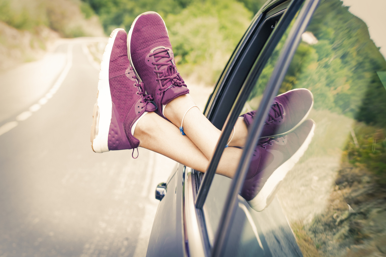 A passenger riding with their feet hanging out of a car window 