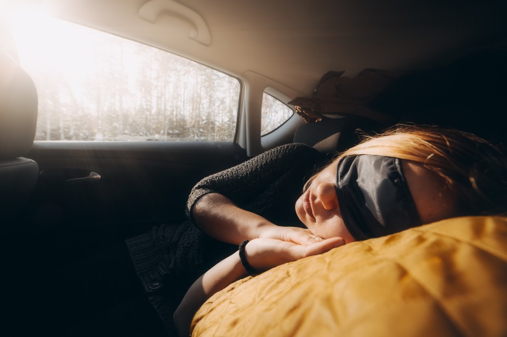 A woman sleeping in the backseat of a car