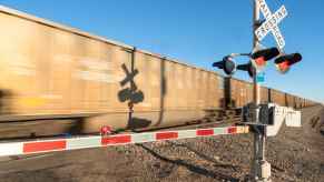 A moving freight train crossing with blue sky in background