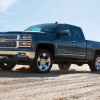 A dark blue 2014 Chevrolet Silverado parked in a dry dusty dirt environment in full left front angle view