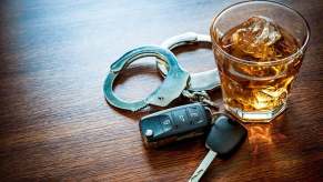 A DUI arrest dramatization places handcuffs with a drink and car keys.