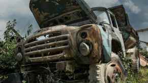 Dump truck abandoned in a parking field with its hood up.