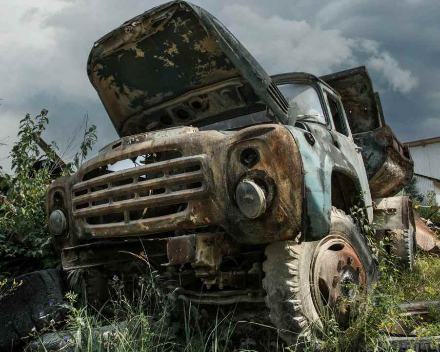 Dump truck abandoned in a parking field with its hood up.