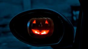 A Jack-o'-lantern, a symbol of Halloween, in a car's mirror.