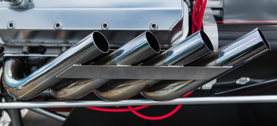 A set of open header exhaust pipes on a custom car build.