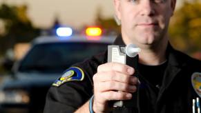 A police officer with a breathalyzer tests for a DUI.