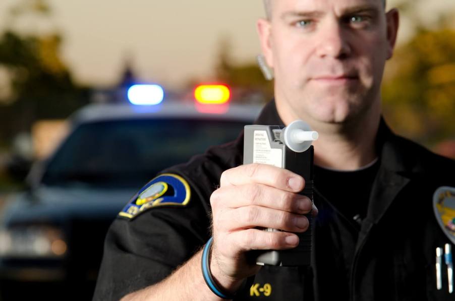 A police officer with a breathalyzer tests for a DUI.