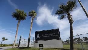 U.S. Space Force sign between palm trees, in front of a base.