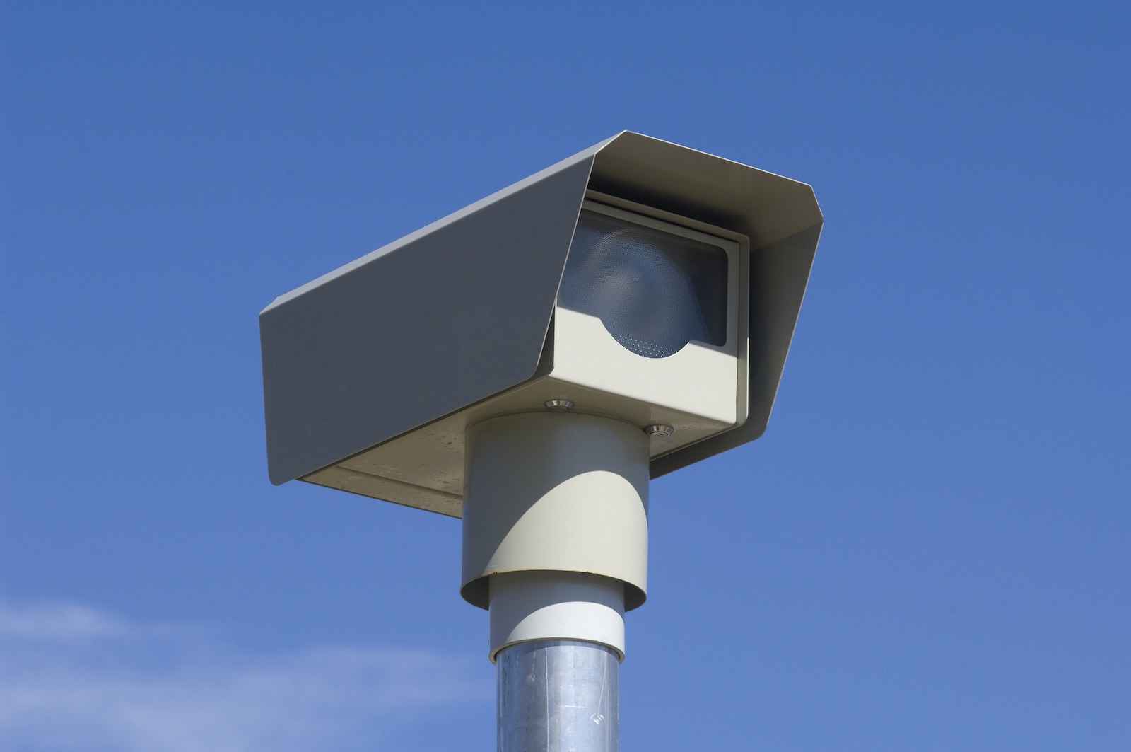 Automatic camera photographs speeders to send tickets, a blue sky in the background.