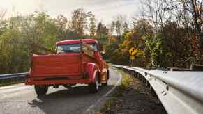 Red farm truck driving down the highway, trees visible in the background