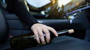 Driver hand on wine bottle laying on right front seat