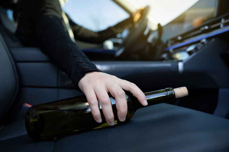 Driver hand on wine bottle laying on right front seat