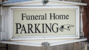 A sign that reads "Funeral Home Parking" with a hand pointing to the right
