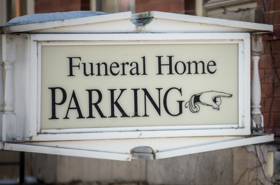 A sign that reads "Funeral Home Parking" with a hand pointing to the right