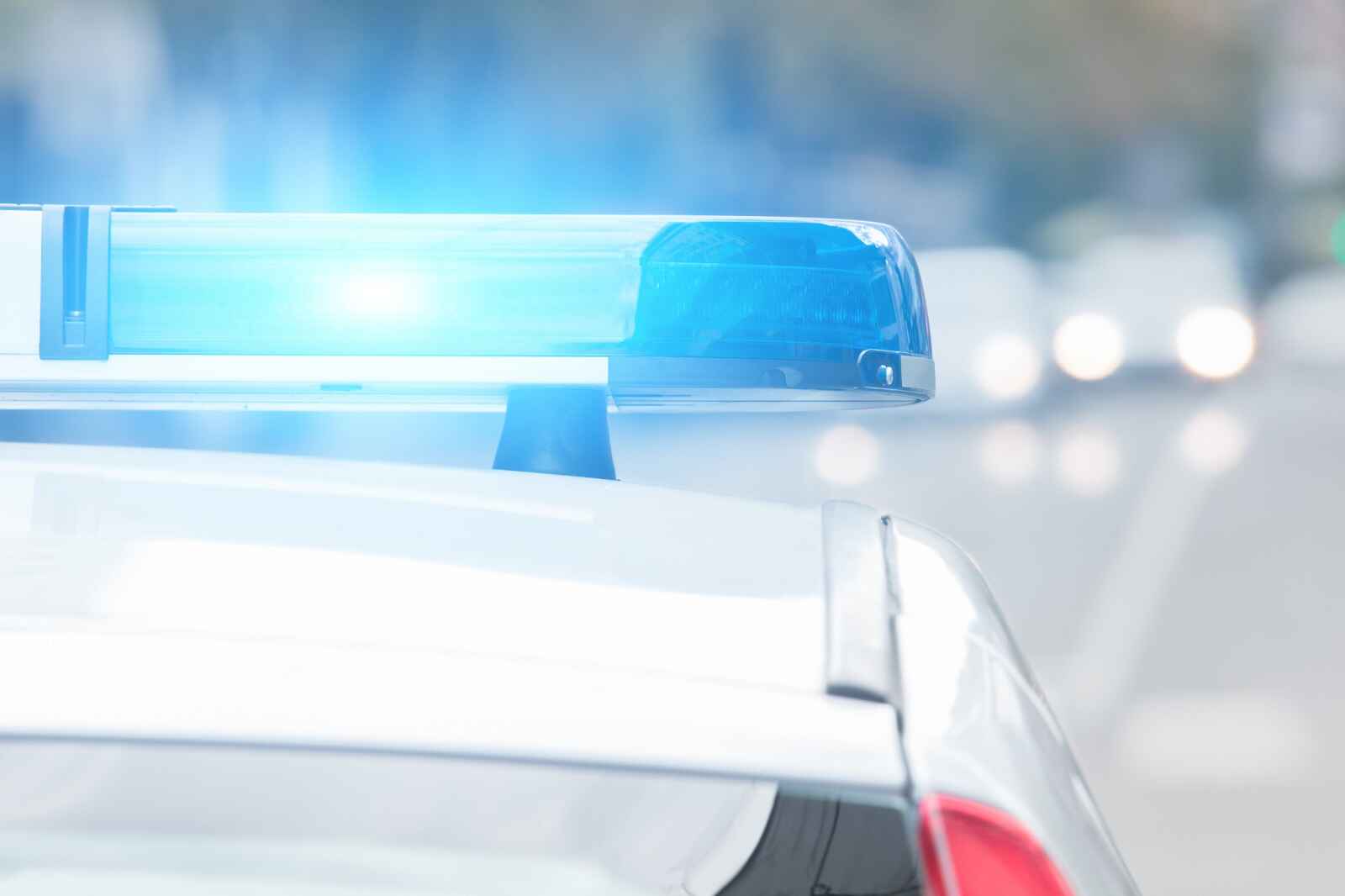 A police cruiser with lights flashing blue in close roof view from behind