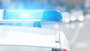 A police cruiser with lights flashing blue in close roof view from behind