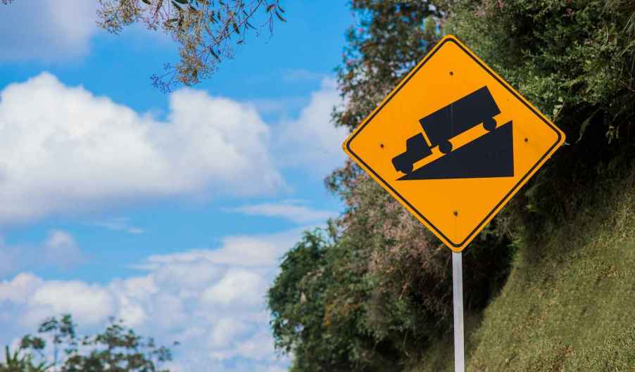 A freeway sign of a semi-truck travelling down a steep incline