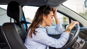 A woman leaning over with balled fist on forehead at steering wheel depiction of getting a dui