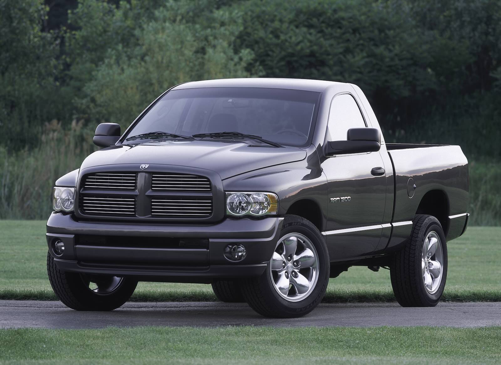 Dark colored regular cab, short bed Ram 1500 parked in front of trees.