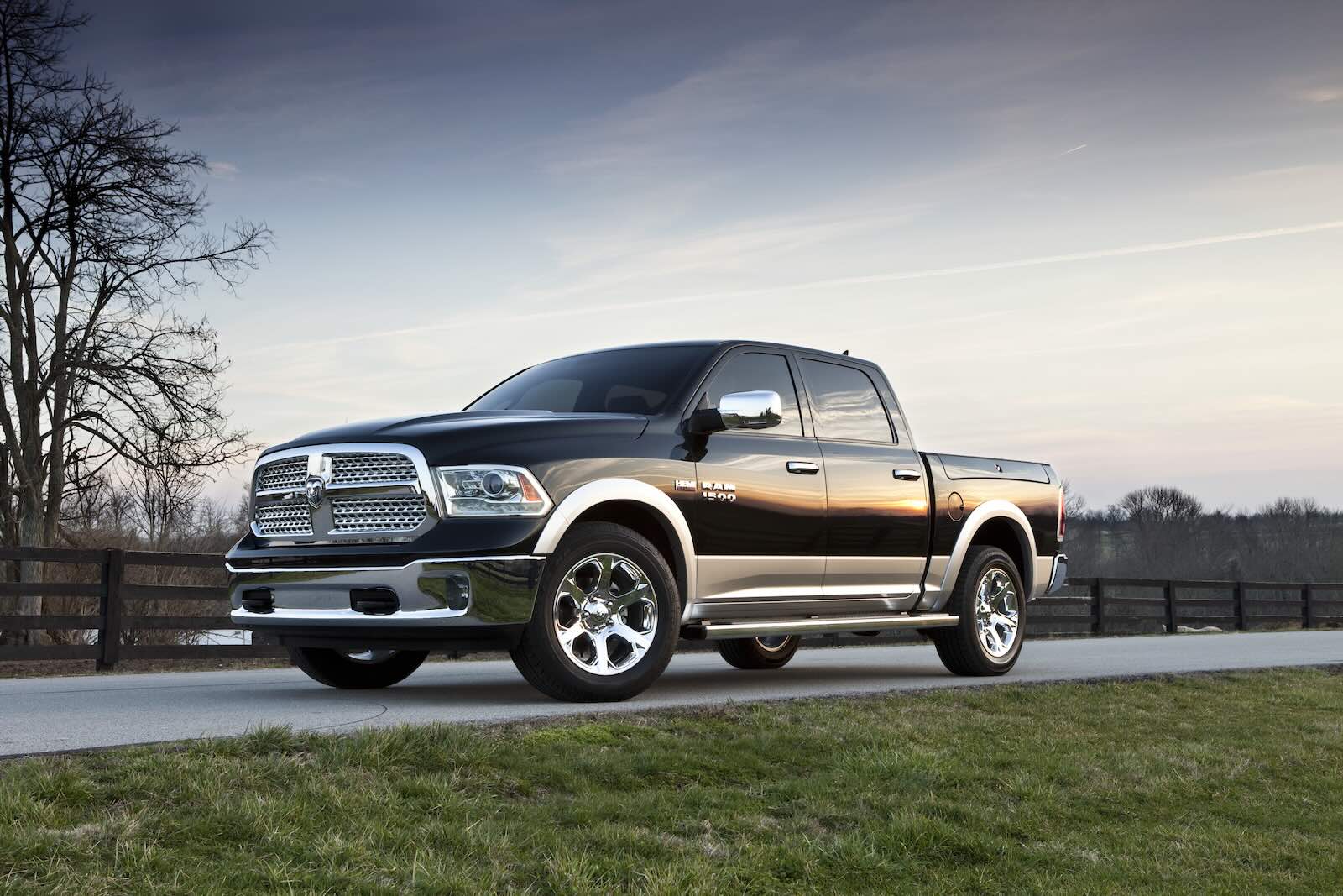 Four door Ram 1500 pickup truck parked on a road, grass visible in the foreground.