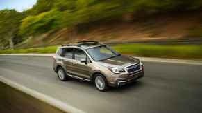 A metallic 2017 Subaru Forester driving on a hilly highway in right front angle view