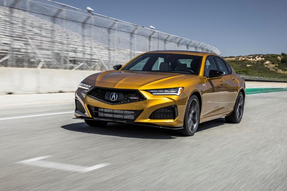 Golden yellow Acura TLX sports sedan driving on a race track