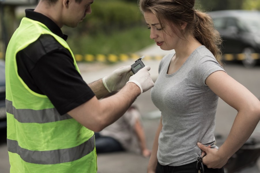 Woman being offered a breathalyzer test on the roadside by a police officer.