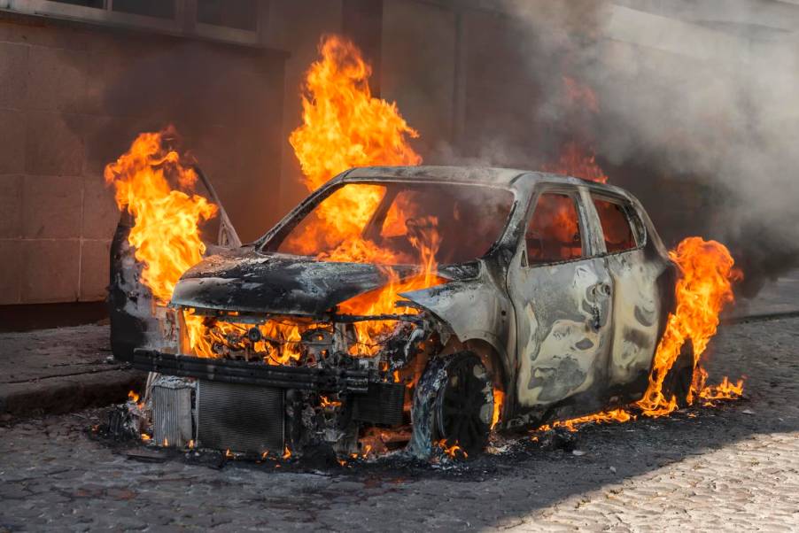 Car parked on a city street and engulfed in flames.