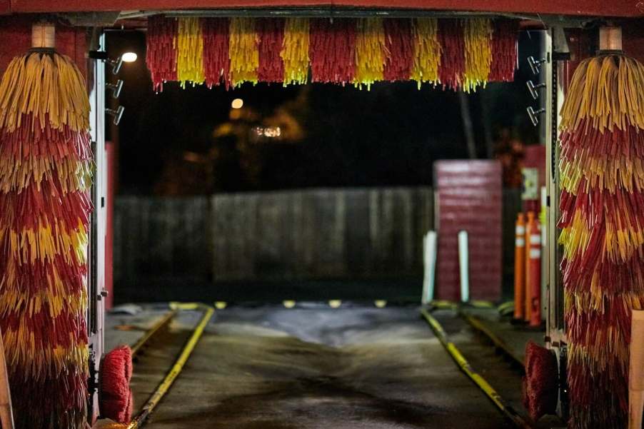 The bright red and yellow bristles of a car wash at night.