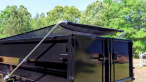 Black dump trailer with a cloth convertible top to protect the cargo.