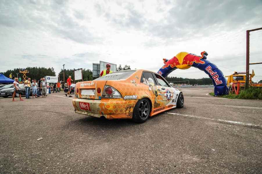 Lexus sedan setup as a drift car parked at a race track.