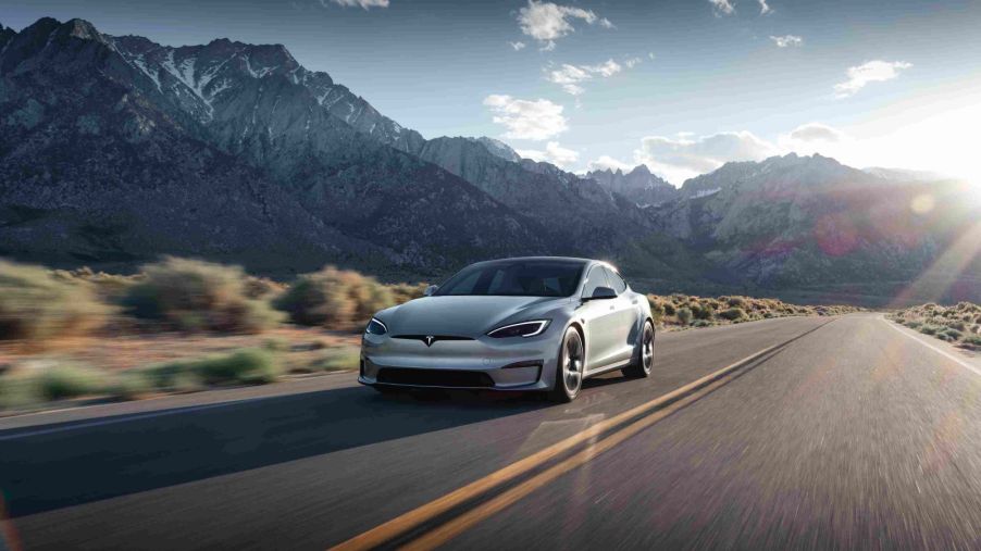 A silver Tesla Model S travels down a mountain highway