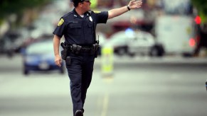 Police officer stands in the middle of the street and holds up his hand to give a command.