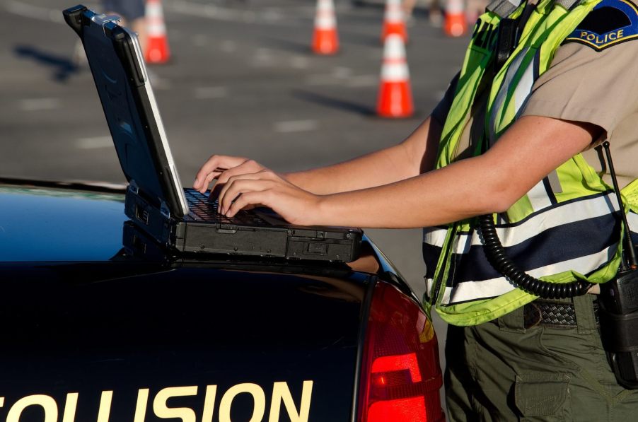 Police officer reading gps car tracker data on a laptop.