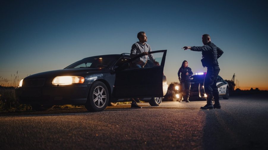A set of police officers pull over a motorist for a field sobriety test.