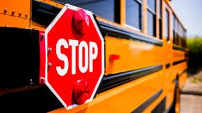 A school bus driver stops and prepares to use its stop sign.