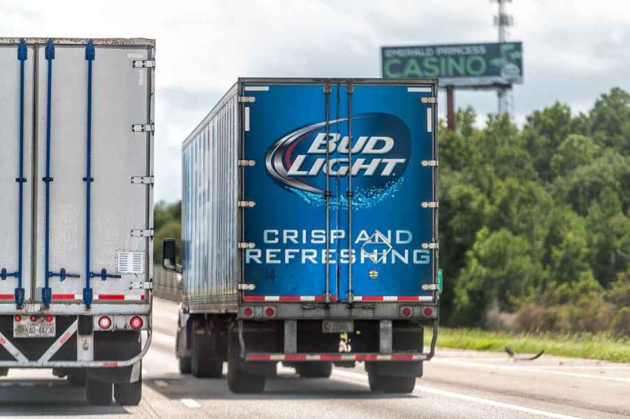 A Budweiser beer semi truck driving away from viewer in right highway lane