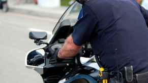 A deputy police officer riding a motorcycle looks over his left shoulder close camera view from behind