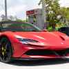 A red Ferrari SF90 Stradale convertible parked at a gas station in close right front angle view