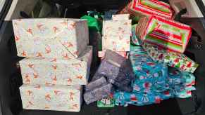Presents gift-wrapped in holiday paper stacked in an SUV's open trunk