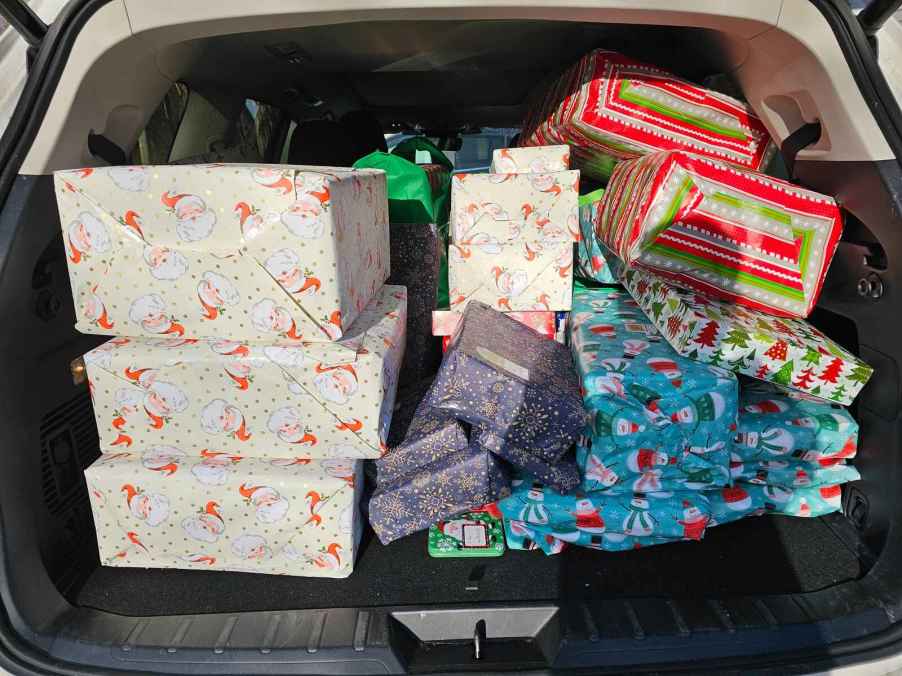 Presents gift-wrapped in holiday paper stacked in an SUV's open trunk