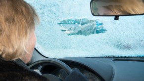 A man driving with ice covering her windshield