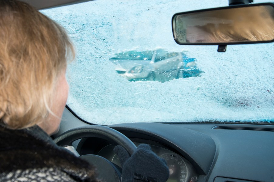 A man driving with ice covering her windshield